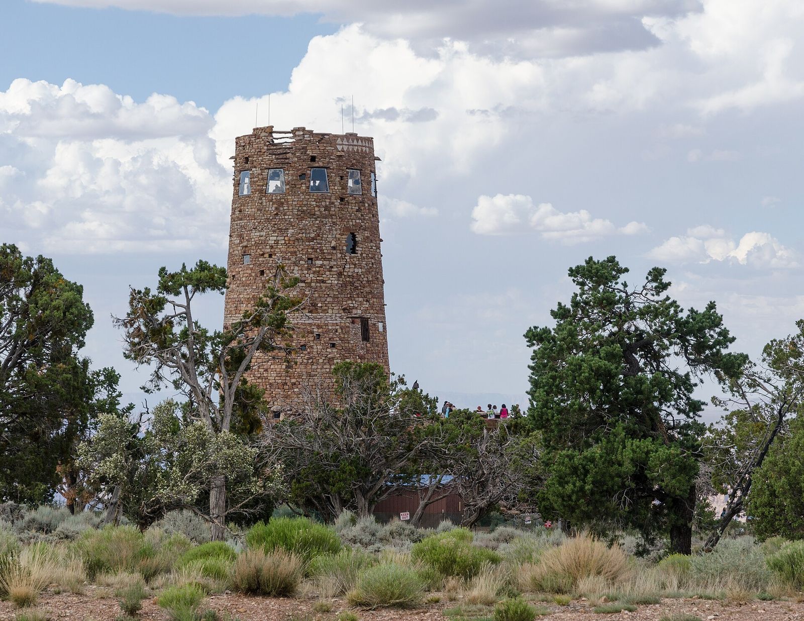 Desert View Watchtower at Grand Canyon South Rim The historic Desert View Watchtower rises above juniper trees on Grand Canyon's South Rim under a cloudy sky.