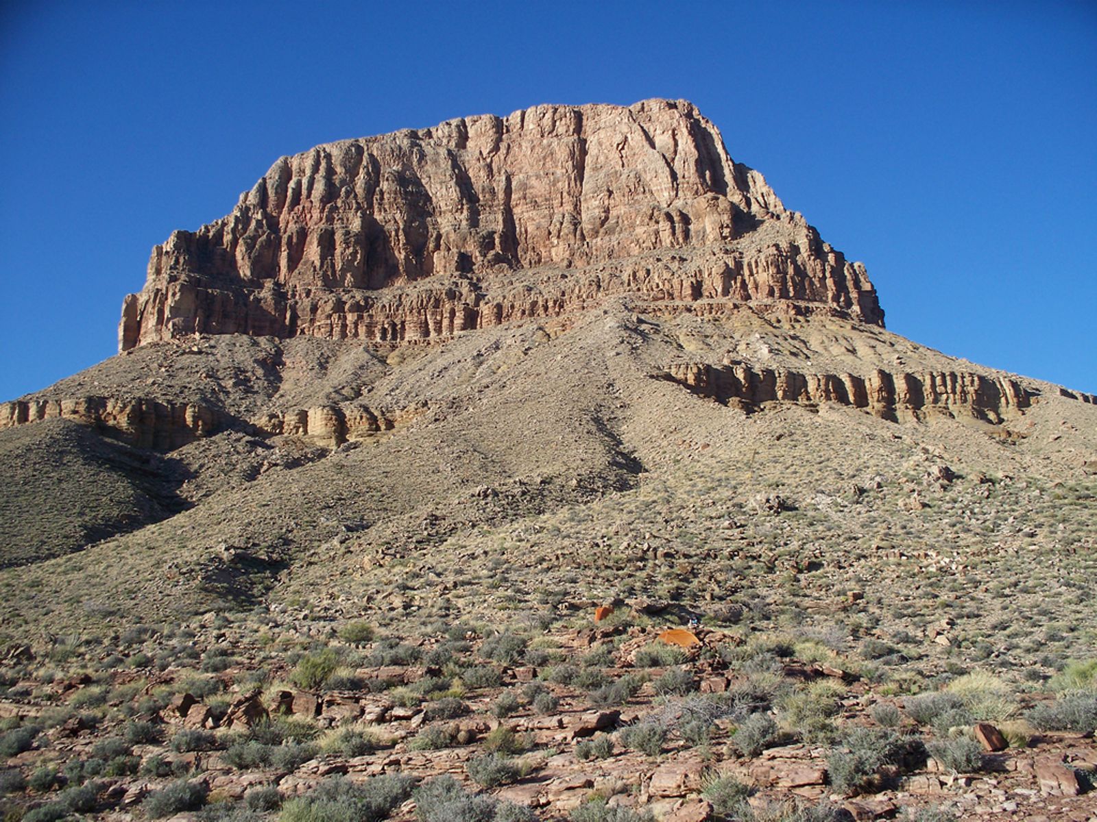 Sumner Butte Rising Above the Inner Canyon A towering red rock butte rises above desert scrub vegetation inside Grand Canyon National Park under clear blue skies.