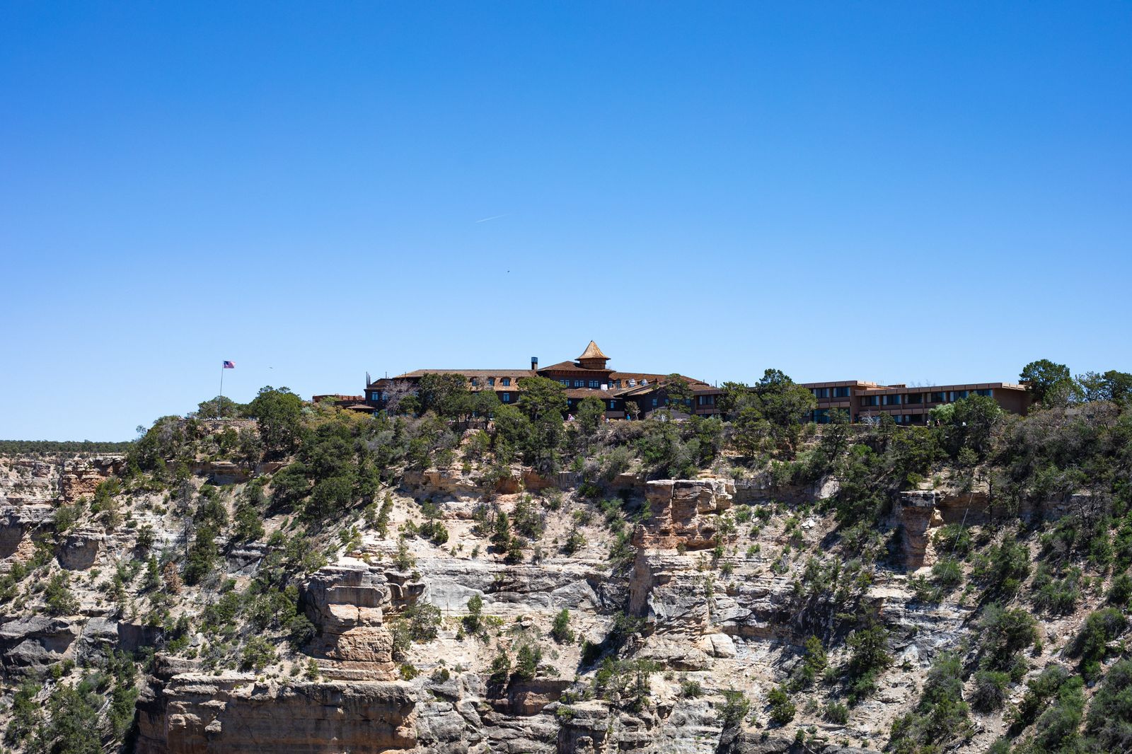 A historic lodge building on the Grand Canyon rim under a clear blue sky