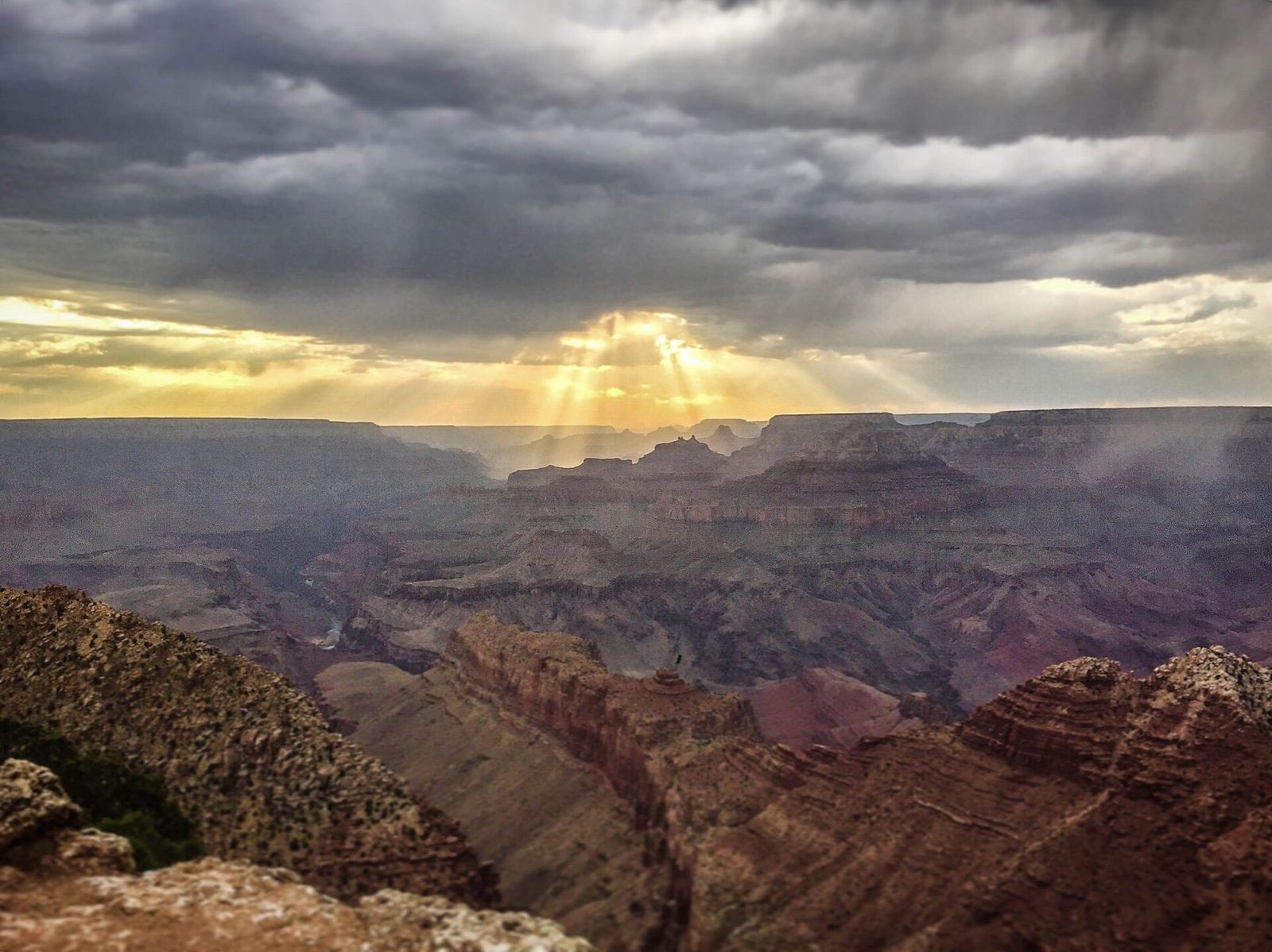 Sun Rays Through Storm Clouds Over Grand Canyon Dramatic sun rays break through storm clouds over the vast layered canyon landscape at Grand Canyon National Park.