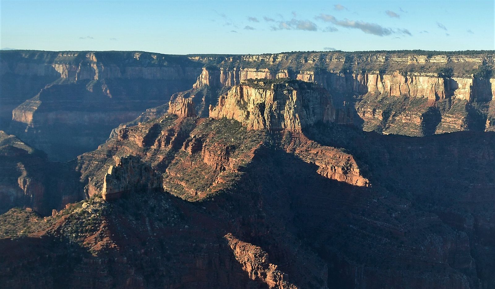 North Rim Buttes at Golden Hour, Grand Canyon Dramatic Grand Canyon buttes and layered red rock cliffs glow in warm early light from the North Rim overlook.