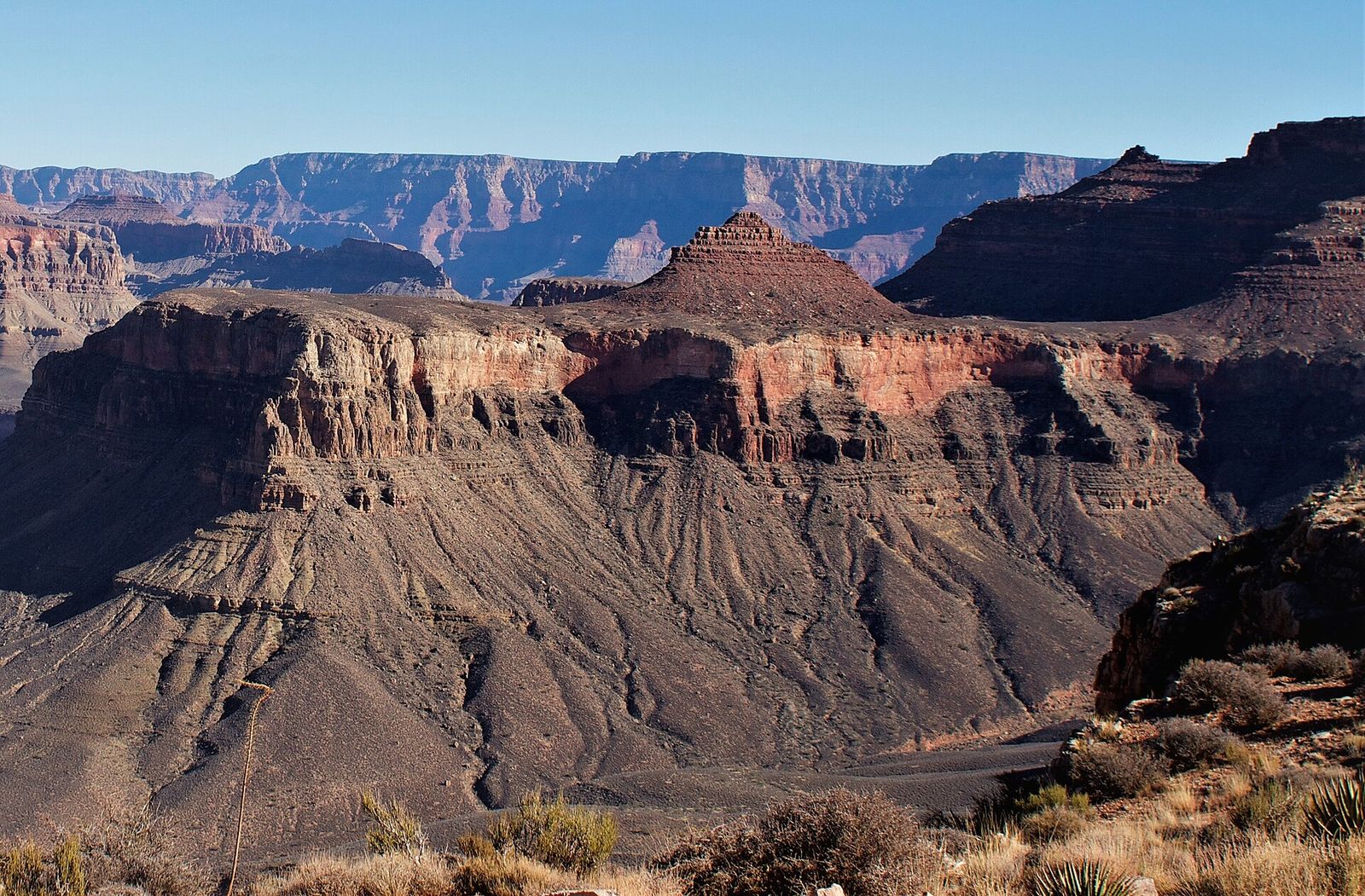 Pattie Butte and Inner Canyon Formations, Grand Canyon Layered red rock buttes and canyon walls stretch deep into Grand Canyon National Park under a clear blue sky.