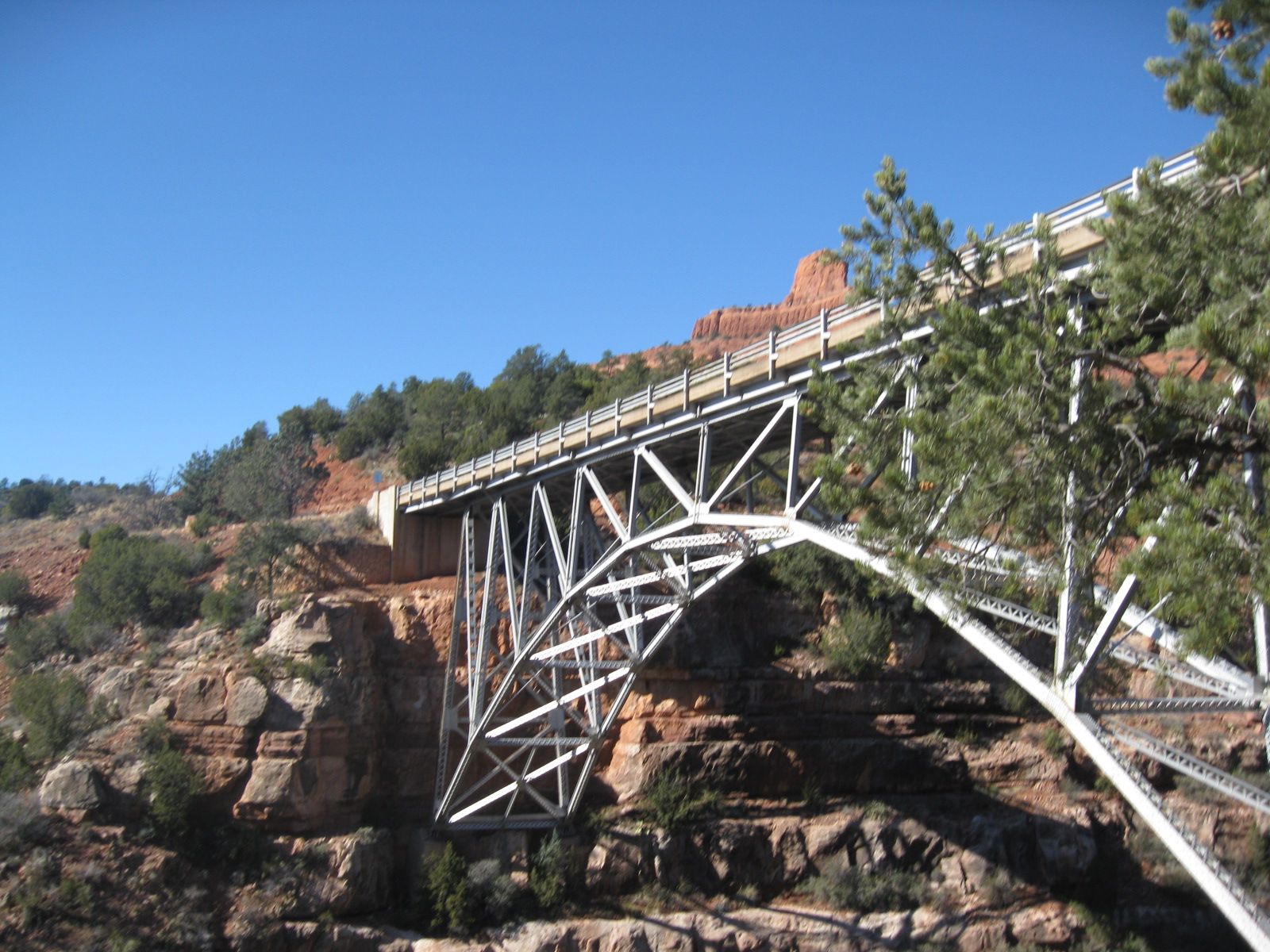 Midgley Bridge steel truss structure spans a red rock canyon near Sedona, Arizona under clear blue skies.