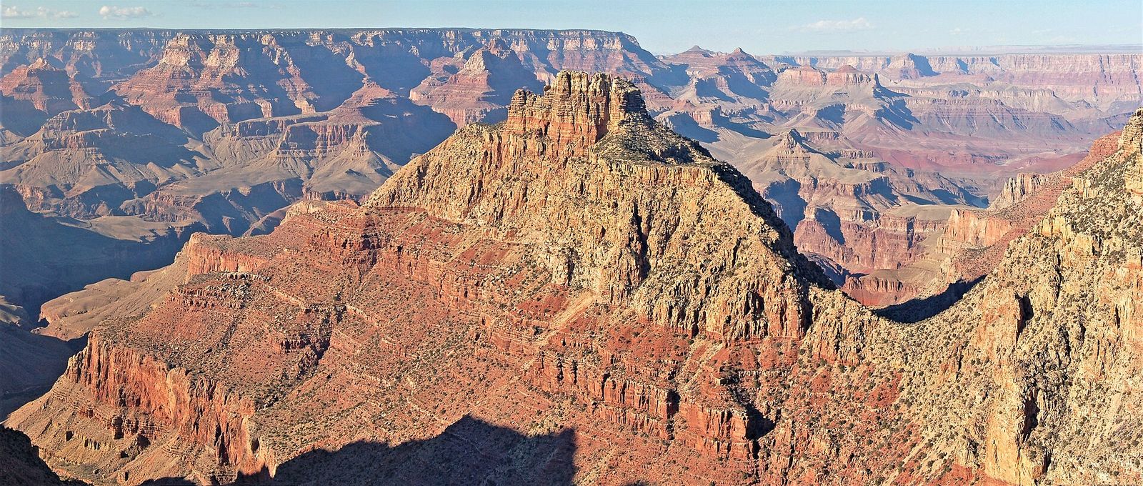 A towering sandstone butte rises above the layered red rock formations of Grand Canyon National Park's South Rim.