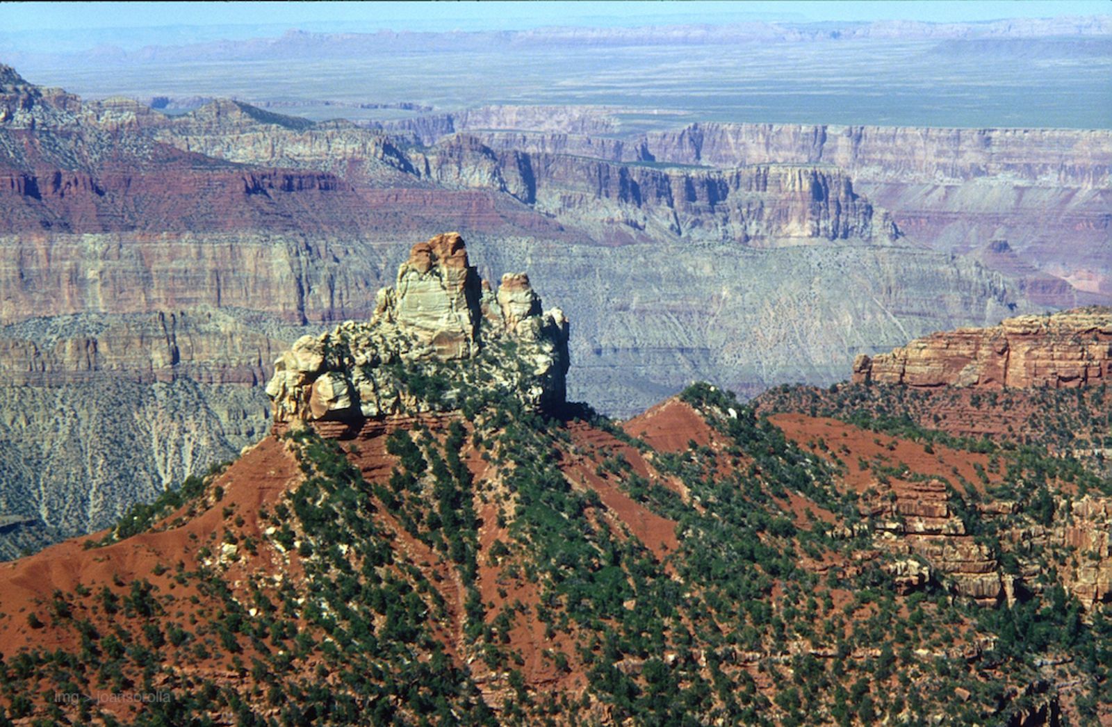 Brady Peak Butte – Grand Canyon North Rim Brady Peak butte rises above red slopes on the Grand Canyon North Rim with layered canyon walls stretching toward the horizon.