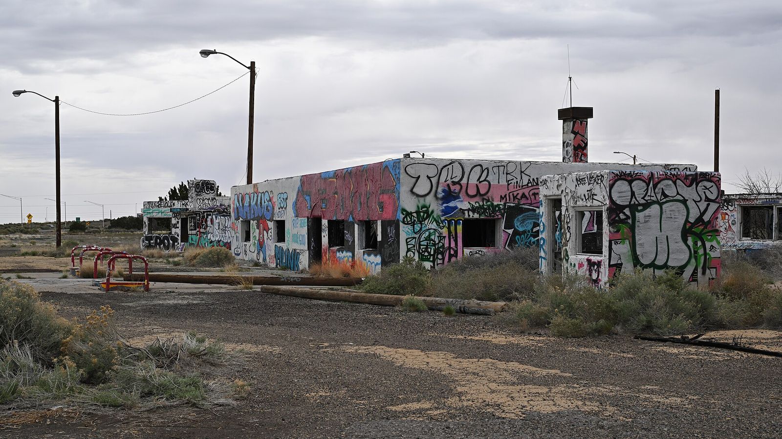 An abandoned graffiti-covered building sits along historic Route 66 near Twin Arrows, Arizona, surrounded by desert scrub.