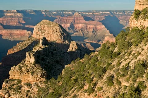 Dramatic Grand Canyon view showing Pollux Temple butte rising above layered red rock canyon walls and the Colorado River below.