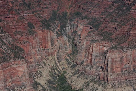 Towering red rock spires and layered canyon walls deep inside Roaring Springs Canyon at the Grand Canyon.