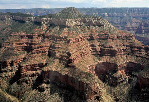 Dragon Head, a flat-topped, forested summit, rises above layered red rock canyon walls in the remote North Rim backcountry.