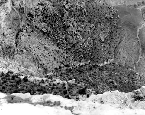 A vintage black-and-white aerial view of Grand Canyon's dramatic steep canyon walls and rocky terrain below Maricopa Point.