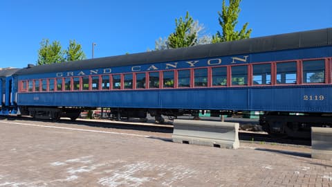 A classic blue Grand Canyon Railway passenger car number 2119 sits at the Williams, Arizona depot under clear skies.