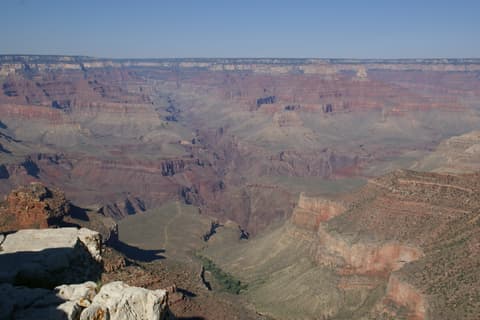 A sweeping panoramic view of the Grand Canyon's layered red and purple rock formations from the South Rim overlook.