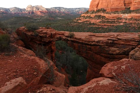 A sweeping view of Devil's Bridge natural sandstone arch overlooking Sedona's iconic red rock canyon landscape.