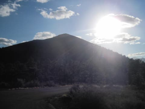 A dramatic sun flare crowns the silhouetted peak of Sunset Crater Volcano in northern Arizona.