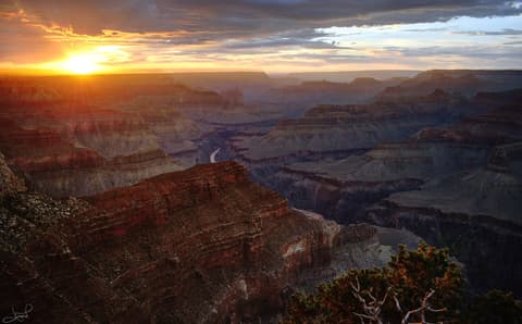 A fiery sunset blazes over the Grand Canyon from Hopi Point, with the Colorado River visible far below.