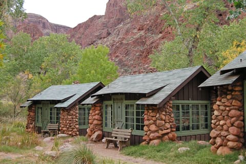 Rustic stone cabins at Phantom Ranch nestled below towering red canyon walls deep inside Grand Canyon National Park.