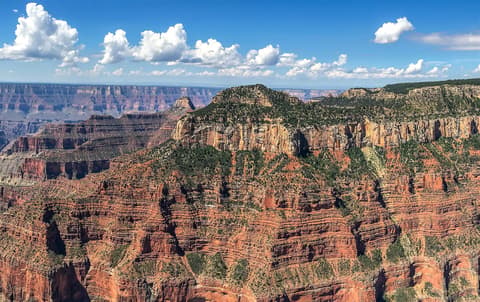 Sweeping panoramic view of Oza Butte and layered red rock canyon walls from Bright Angel Point on the North Rim.
