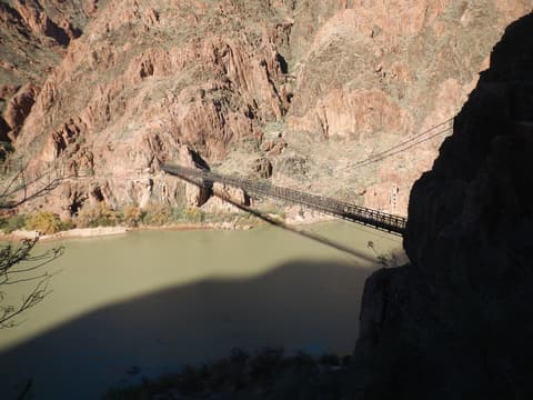 The Black Bridge suspension bridge spans the muddy green Colorado River deep inside Grand Canyon National Park.