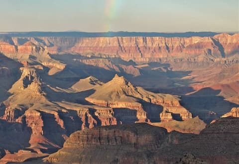 Sweeping Grand Canyon panorama revealing Solomon Temple butte, layered red rock formations, and the Colorado River winding far below.