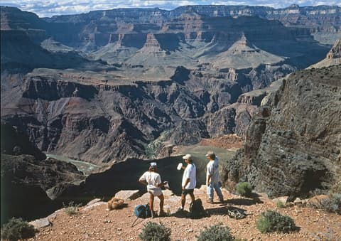 Three hikers stand at Skeleton Point on the South Kaibab Trail overlooking the Colorado River deep in Grand Canyon.