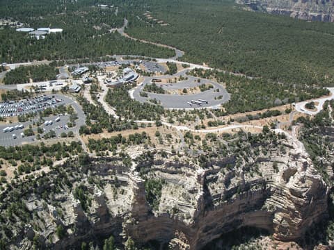 Aerial view of Grand Canyon South Rim Visitor Center, parking lots, and canyon rim edge below.