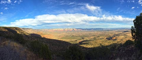 A sweeping panoramic view of the Sedona, Arizona landscape with red rock formations under dramatic clouds.