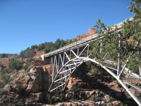 Midgley Bridge steel truss structure spans a red rock canyon near Sedona, Arizona under clear blue skies.
