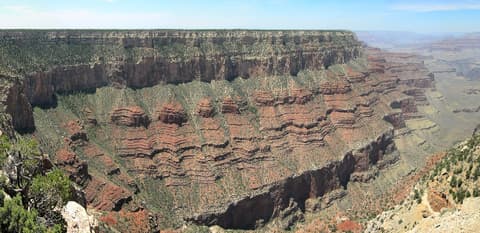 A sweeping panoramic view of layered red rock canyon walls and buttes at Pipe Creek Vista on the South Rim.