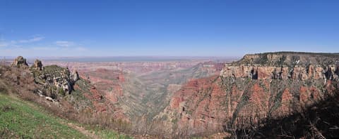 A sweeping panoramic view from Roosevelt Point on the North Rim of Grand Canyon National Park under clear blue skies.