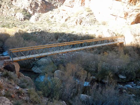 A metal footbridge spans Bright Angel Creek along the Ribbon Falls Trail deep inside the Grand Canyon.