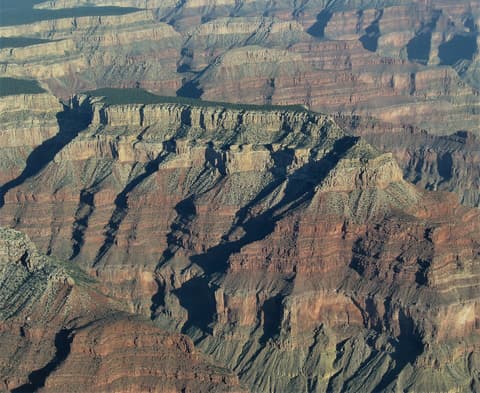 Aerial view of Diana Temple butte rising above deeply layered red rock canyon walls at Grand Canyon's South Rim.