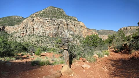 A rustic wooden trail junction sign marks the Hermit Trail and Waldron Trail split on the Grand Canyon South Rim.