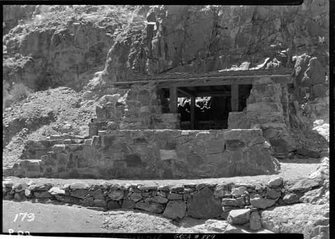 A historic stone masonry resthouse along Bright Angel Trail nestled against rugged Grand Canyon rock walls.