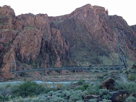 The Silver Bridge spans the Colorado River deep inside Grand Canyon, framed by towering red rock cliffs.